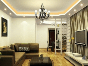 Modern living room with brown sectional sofa, coffee table, wall-mounted TV, wooden flooring, and decorative lighting featuring the LED Downlight Alkor 7W 3. Dining area is visible in the background.